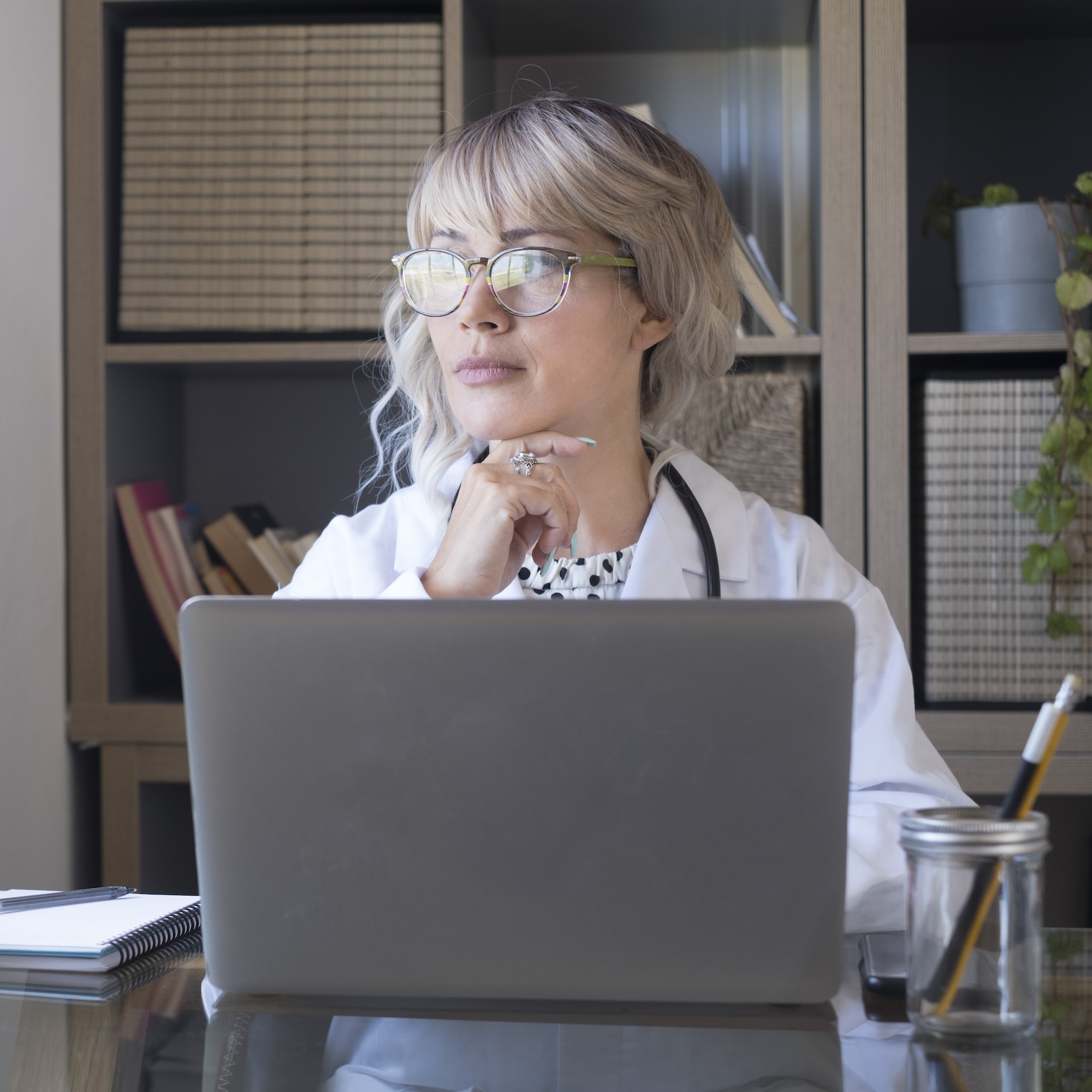 Female doctor in front of a laptop working from home studio. Modern medical office with woman