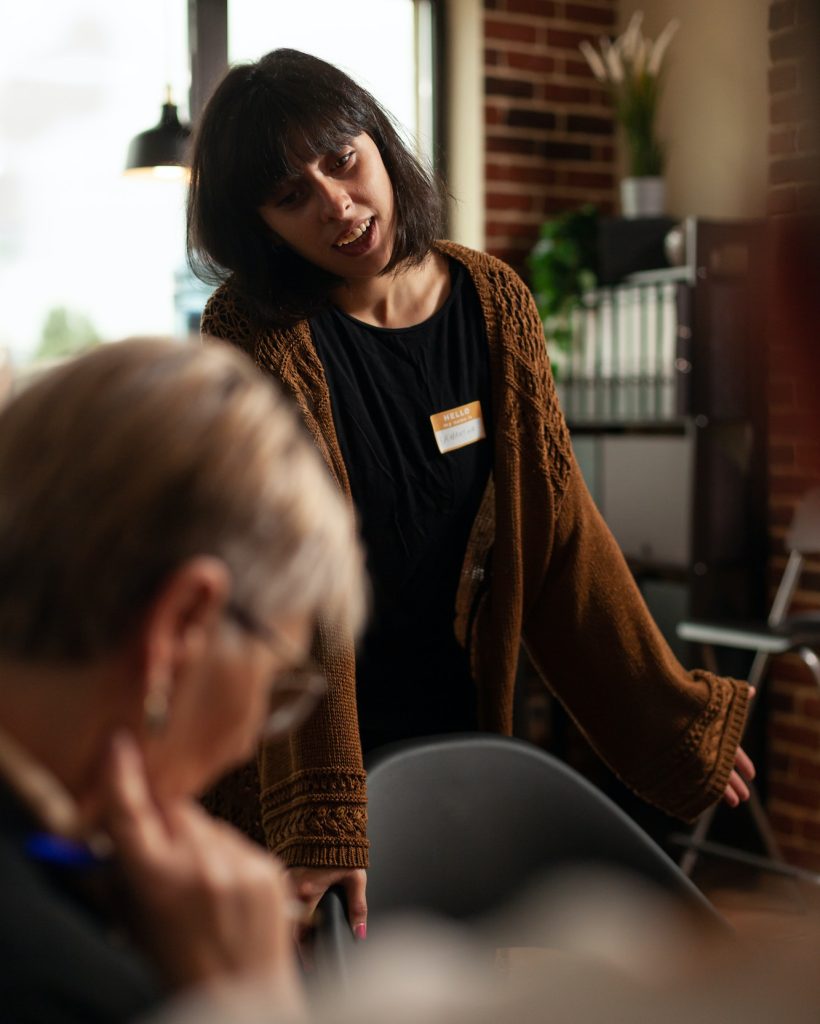woman-smiling-and-talking-about-recovery-with-people-at-aa-therapy-meeting.jpg